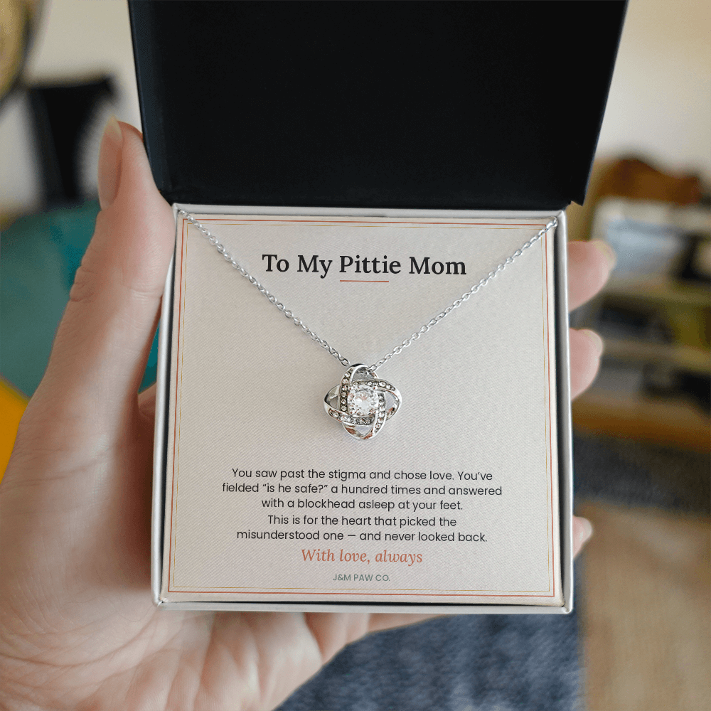 Pittie Mom Love Knot necklace held in hand showing pendant and message card