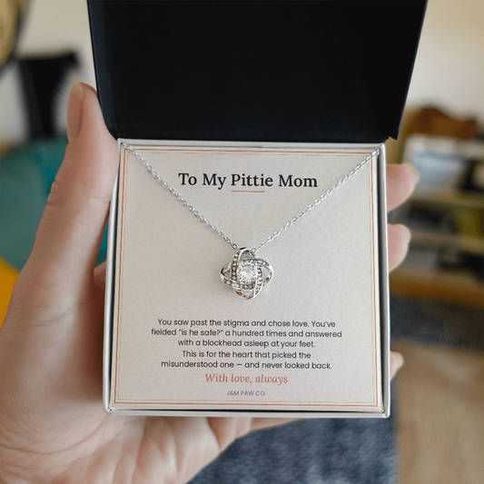 Pittie Mom Love Knot necklace held in hand showing pendant and message card